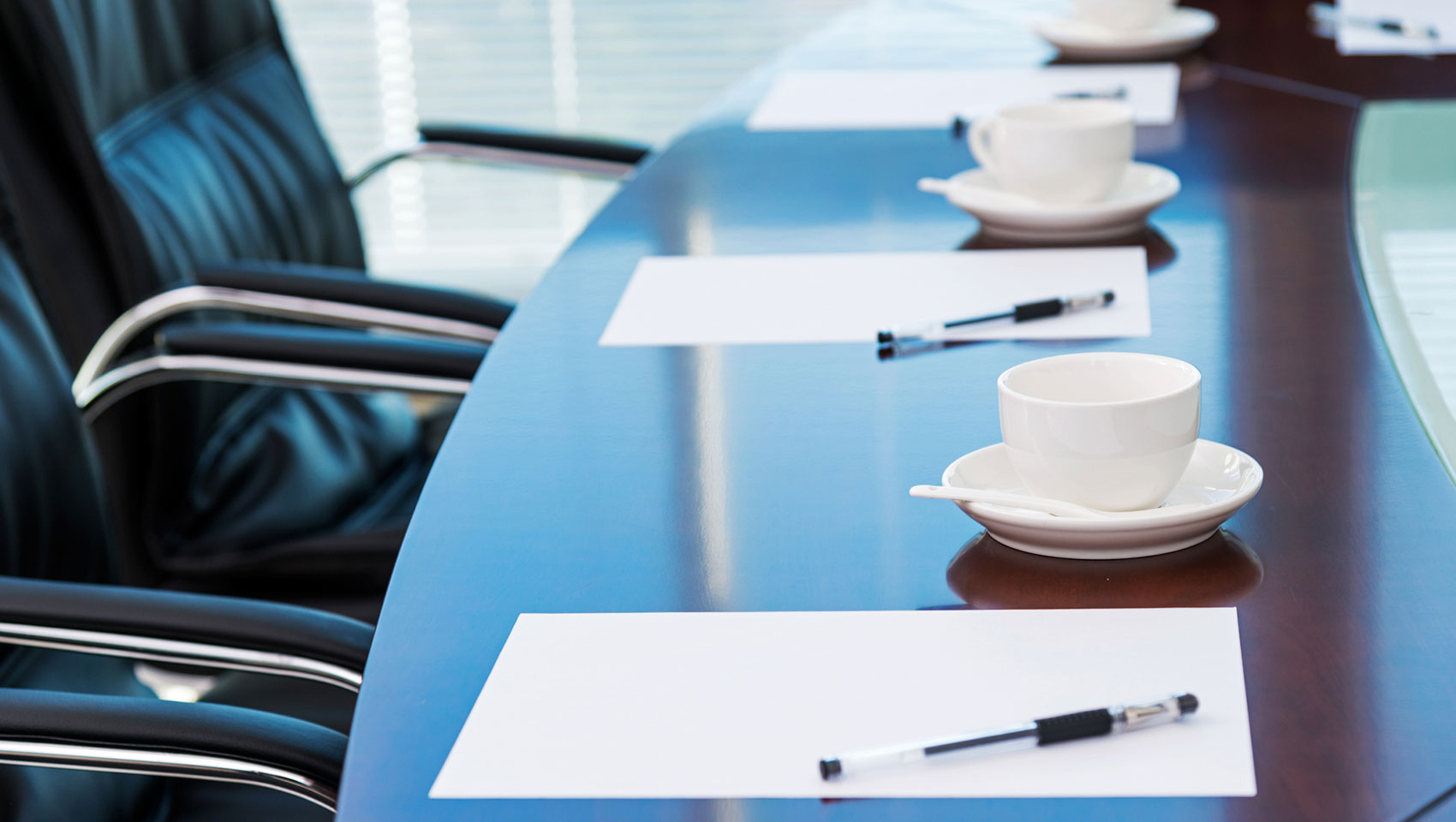 Conference table with paper, pens and coffee cups