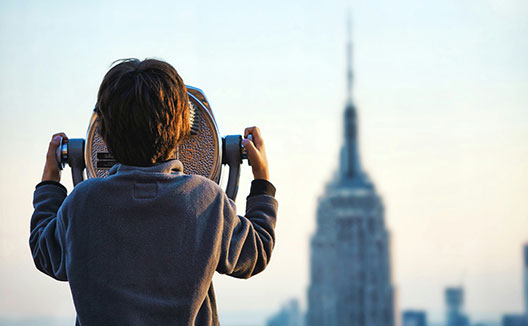 child looking through binoculars at NYC skyline from top of the rock